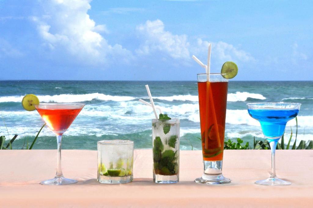 four cocktails on a table with the ocean in the background at The Beach Cabanas Retreat & Spa in Koggala