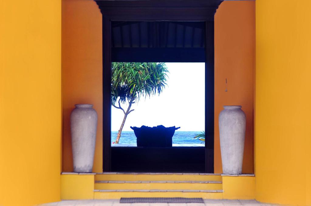 a window with a view of the ocean and a palm tree at The Beach Cabanas Retreat & Spa in Koggala