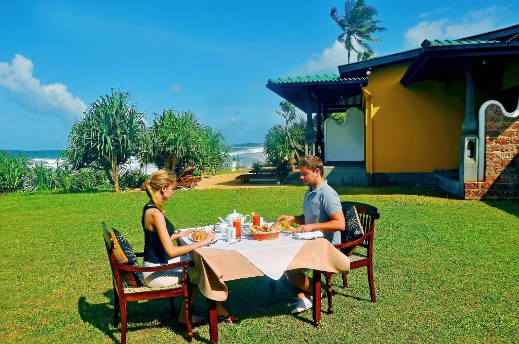 a man and woman sitting at a table at The Beach Cabanas Retreat & Spa in Koggala