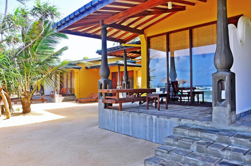 a patio of a house with a wooden table at The Beach Cabanas Retreat & Spa in Koggala