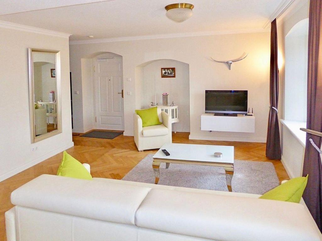 a living room with a white couch and a tv at Jagdschloß zu Hohen Niendorf Fewo 1 ELEONORE in Hohen Niendorf
