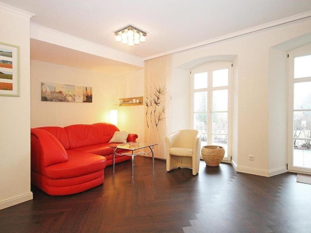 a living room with a red couch and a table at Jagdschloß zu Hohen Niendorf Fewo 2 in Hohen Niendorf