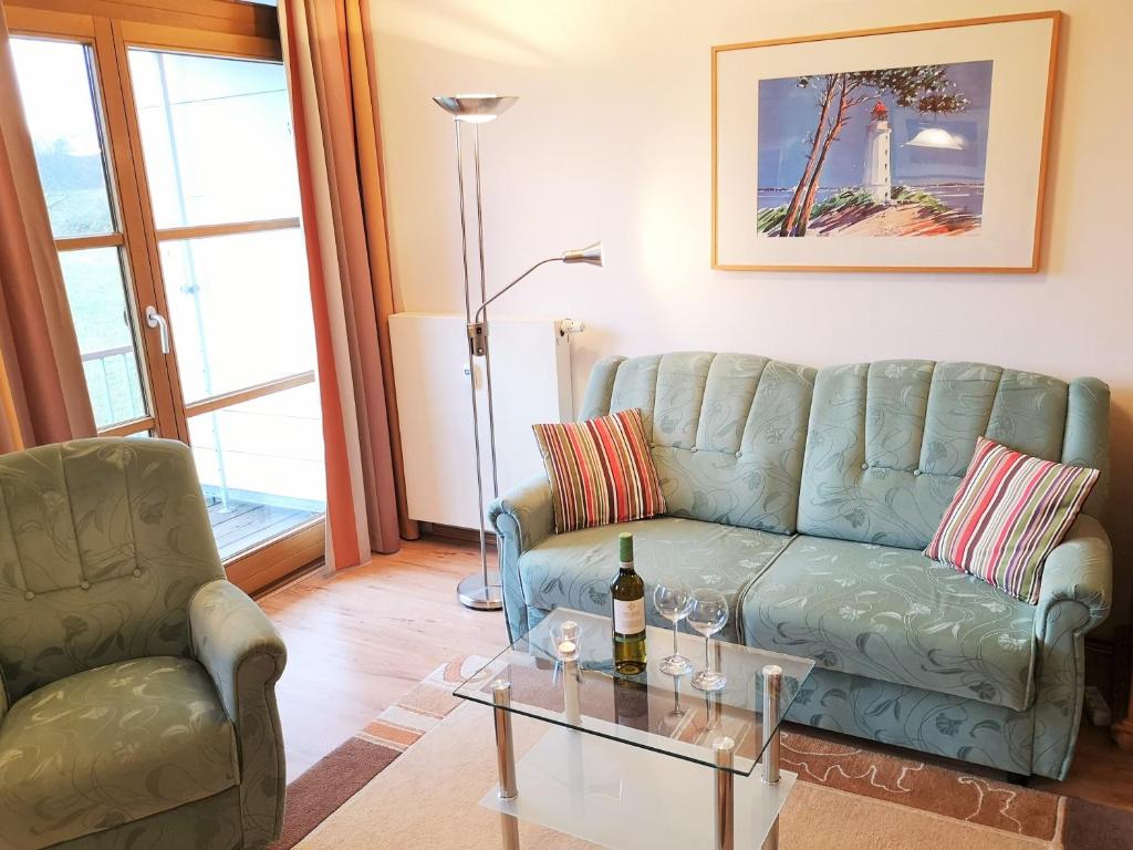 a living room with a blue couch and a glass table at Appartementanlage Am Grün 13 in Wittenbeck