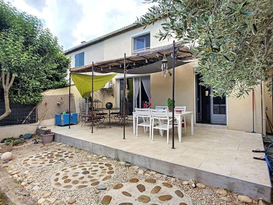 un patio avec une table blanche et un parasol jaune dans l'établissement maison 3 chambres piscine près Avignon 4 jours minimum, au Pontet