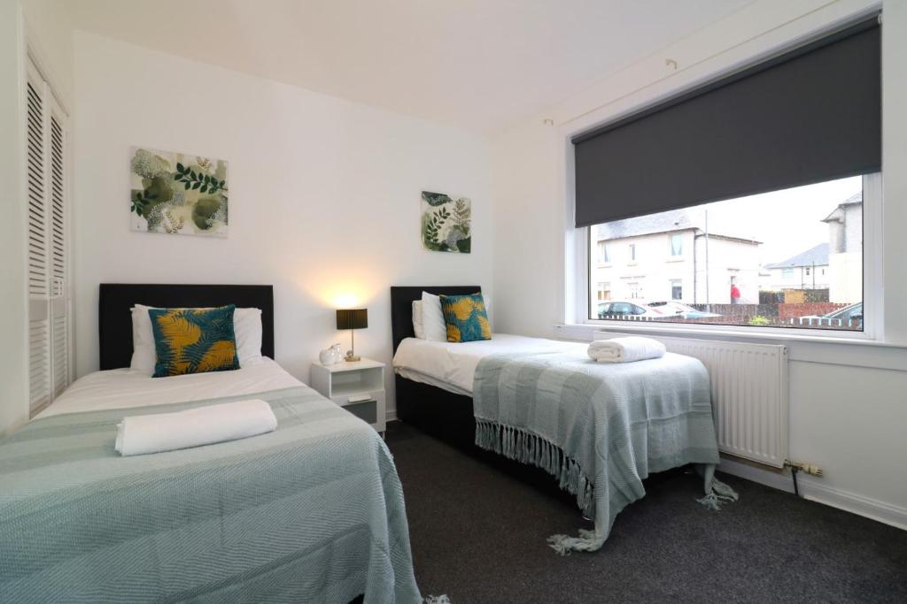 a bedroom with two beds and a large window at Signature - Glen Lee House in Glasgow