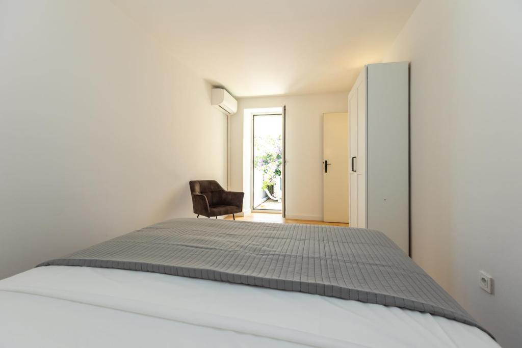 a bedroom with a white bed and a black chair at House Draza in Biograd na Moru