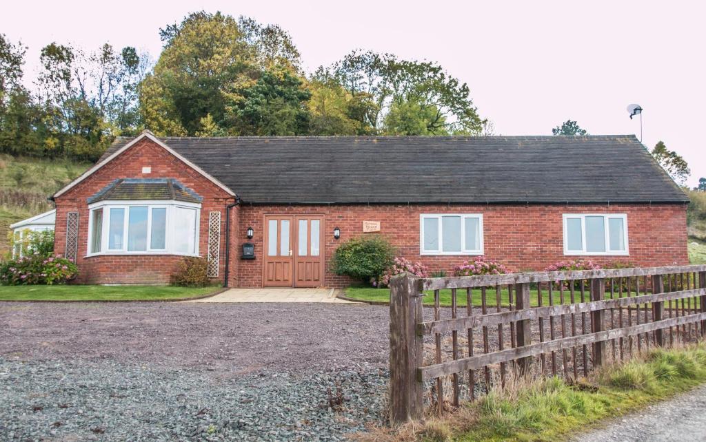 a red brick house with a wooden fence at Applewood in Much Wenlock