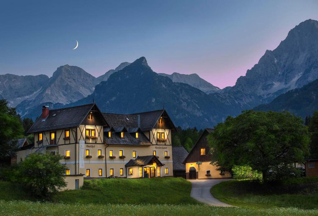 a large house on a hill with mountains in the background at Landhotel Gressenbauer in Hinterstoder