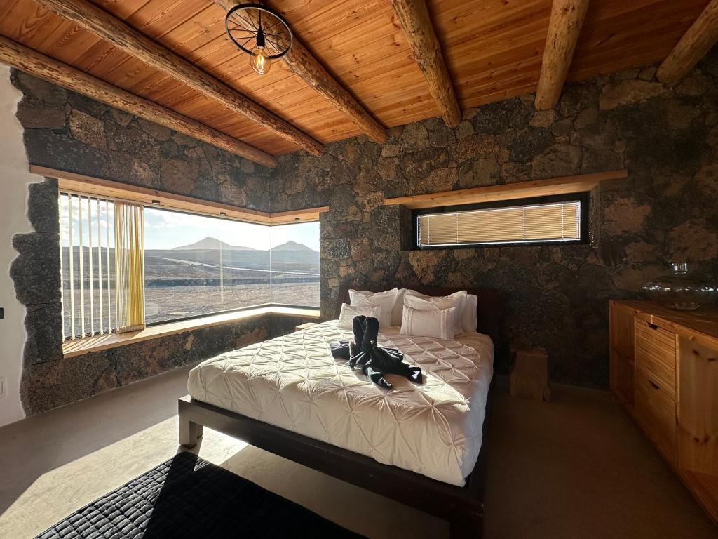 a bedroom with a bed and a large window at Casita Tahona con vistas de infarto al mar y volcanes con absoluta privacidad in Parque Holandes