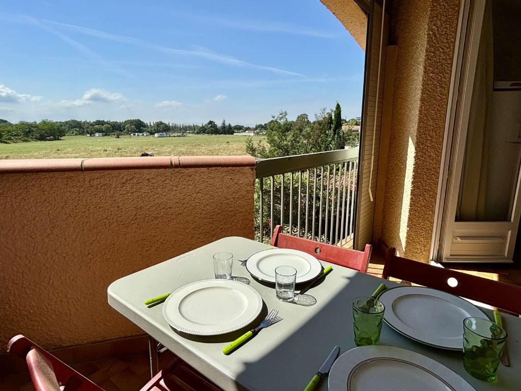 une table blanche avec des assiettes et des verres sur un balcon dans l'établissement Appartement 2 pièces avec parking privé à 300m de la plage - Argelès-sur-Mer - FR-1-225-62, à Argelès-sur-Mer