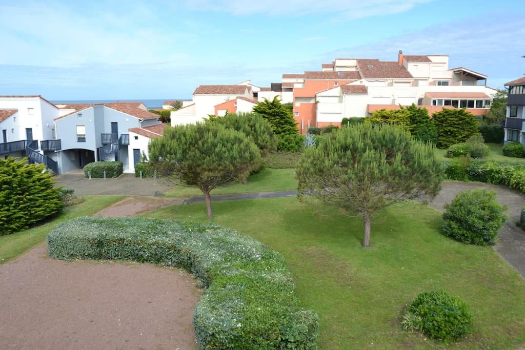 un jardin avec des buissons, des arbres et des maisons dans l'établissement Appartement Capbreton, à Capbreton