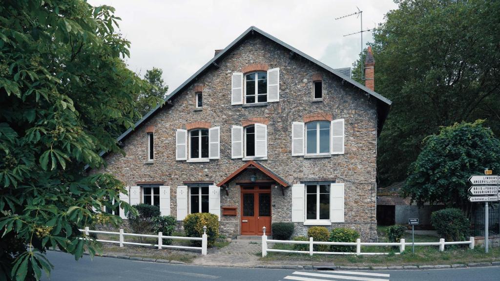 een bakstenen huis met witte ramen en een rode deur bij L'Auberge 91530 in Le Val-Saint-Germain