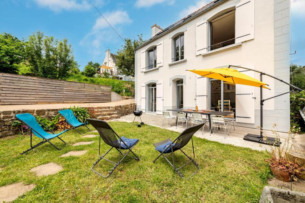 2 chaises et un parasol dans la cour d'une maison dans l'établissement Heolenn - Maison proche mer et circuits randonnées, à Plougastel-Daoulas