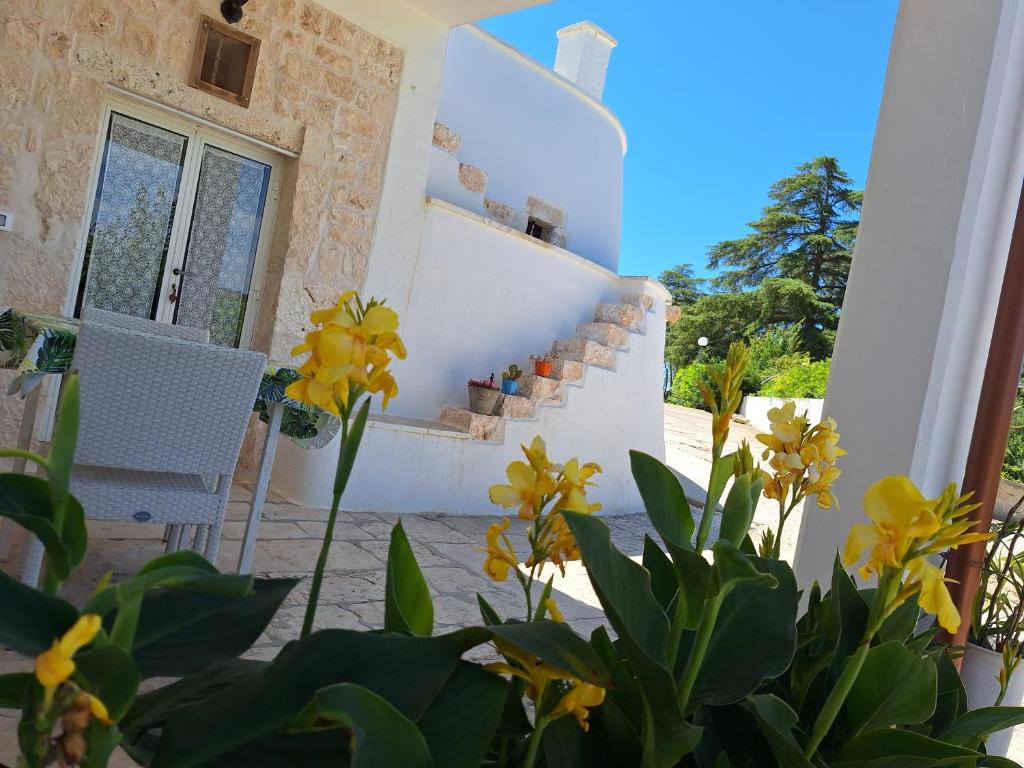 een huis met witte muren en gele bloemen bij Holiday Home Trullo Antico in Ostuni