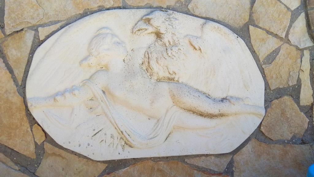 a statue of a man playing a instrument on a stone wall at Holiday Rome Hub Villa Camilla in Fiumicino