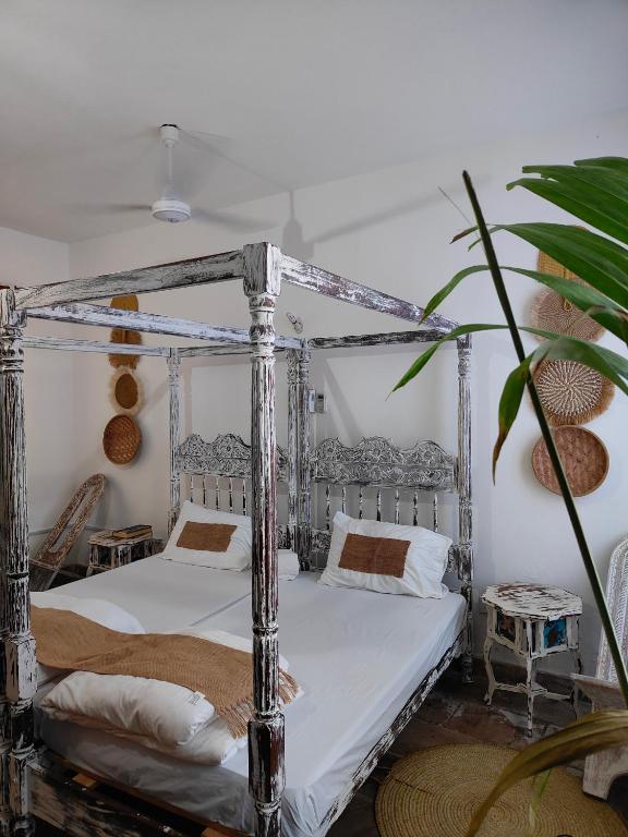 a bedroom with two beds and a plant at Diani Beach Cottage Apartment in Ukunda