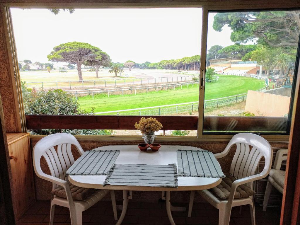 une table et des chaises dans une pièce avec une fenêtre dans l'établissement Duplex Port Hyères Plage Vue Hippodrome, à Hyères