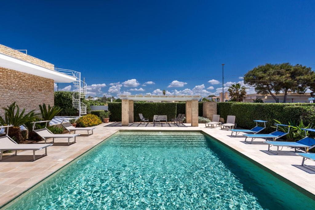 a swimming pool with lounge chairs and a swimming pool at Villa Miramare by Perle di Puglia in Torre Suda