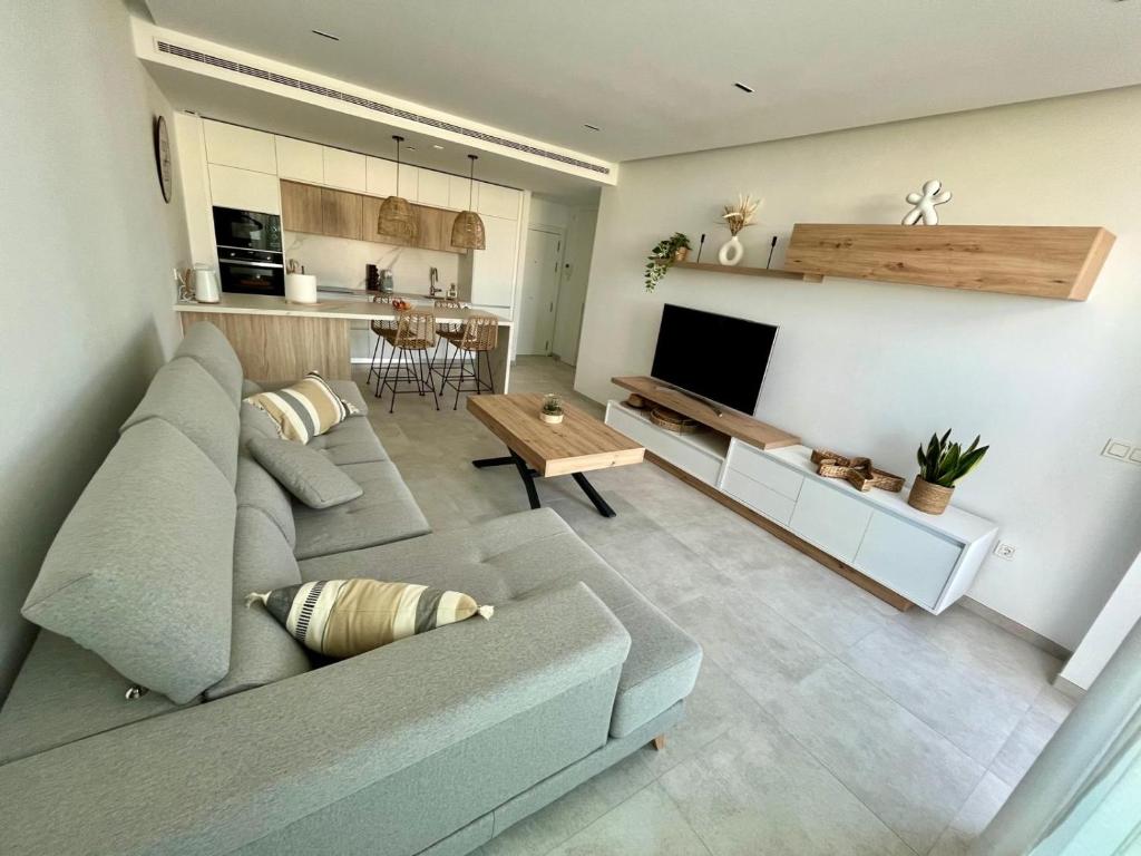 ein Wohnzimmer mit einer Couch, einem Fernseher und einem Tisch in der Unterkunft Costa Ballena & Eleven Lights in Chipiona
