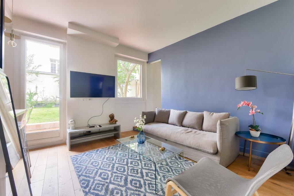 un salon avec un canapé et une télévision dans l'établissement Paris Garden Luxury next to Eiffel Tower, à Paris