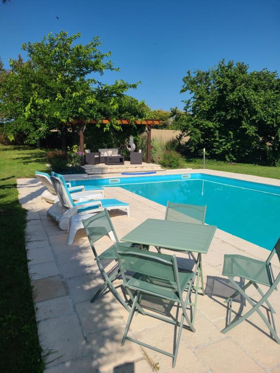 - une table et des chaises à côté de la piscine dans l'établissement la galandière, à Mensignac