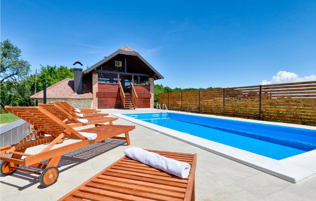 a swimming pool with two deck chairs and a house at 2 Bedroom Amazing Home In Jalzabet in Jalžabet