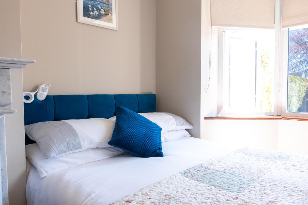 a bed with blue and white pillows and a window at AVALON HOUSE in Galway