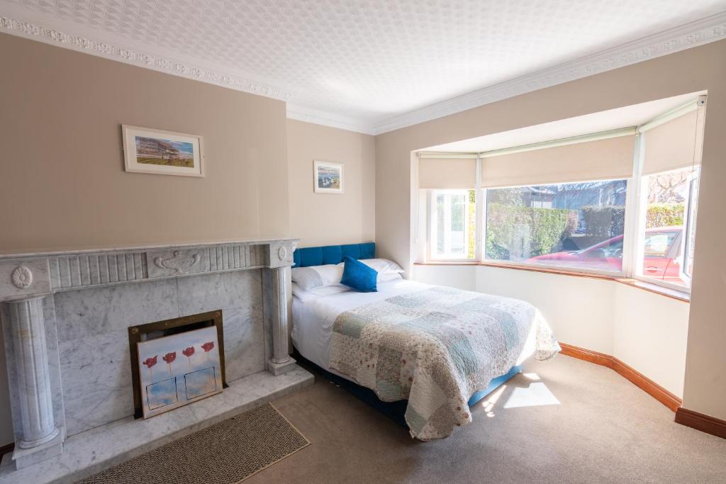a bedroom with a bed and a fireplace and a window at AVALON HOUSE in Galway