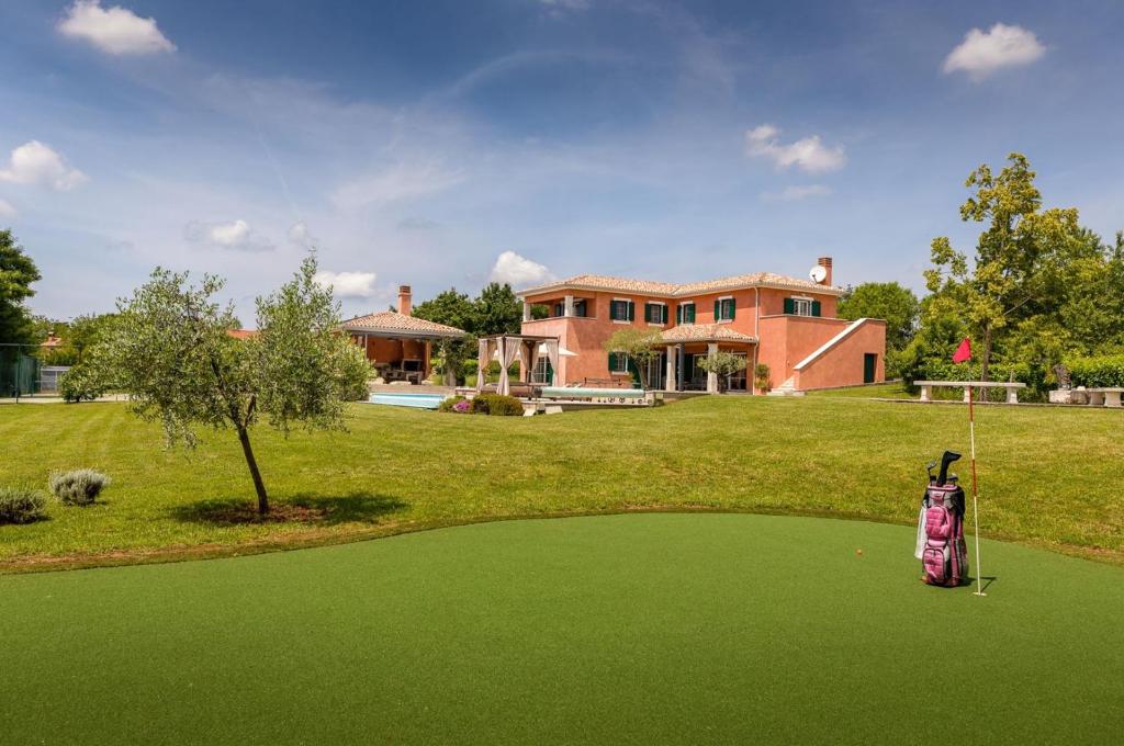 a golf course with a house in the background at Villa Village by Villsy - with heated pool, spa, private tennis court, golf court, basketball court and playroom in Tinjan