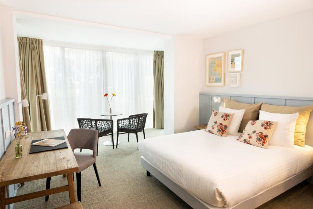 une chambre d'hôtel avec un lit et un bureau et une chambre dans l'établissement Eco-Domaine La Fontaine - HOTEL-SPA - Plage de la Fontaine aux Bretons, à Pornic