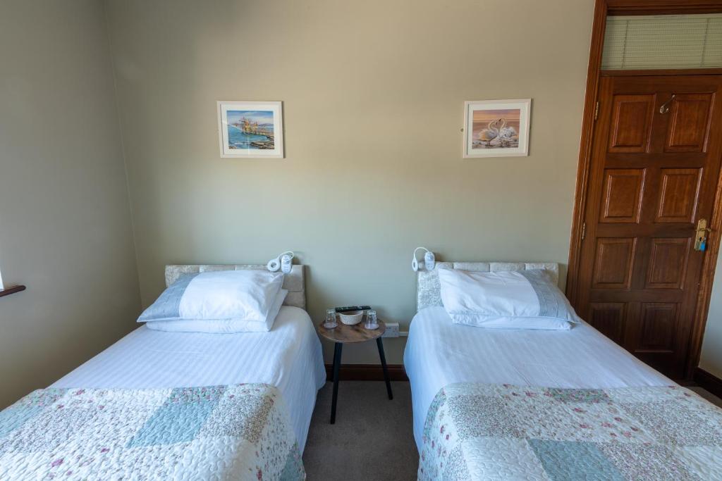 two beds in a room with a door and a table at AVALON HOUSE in Galway