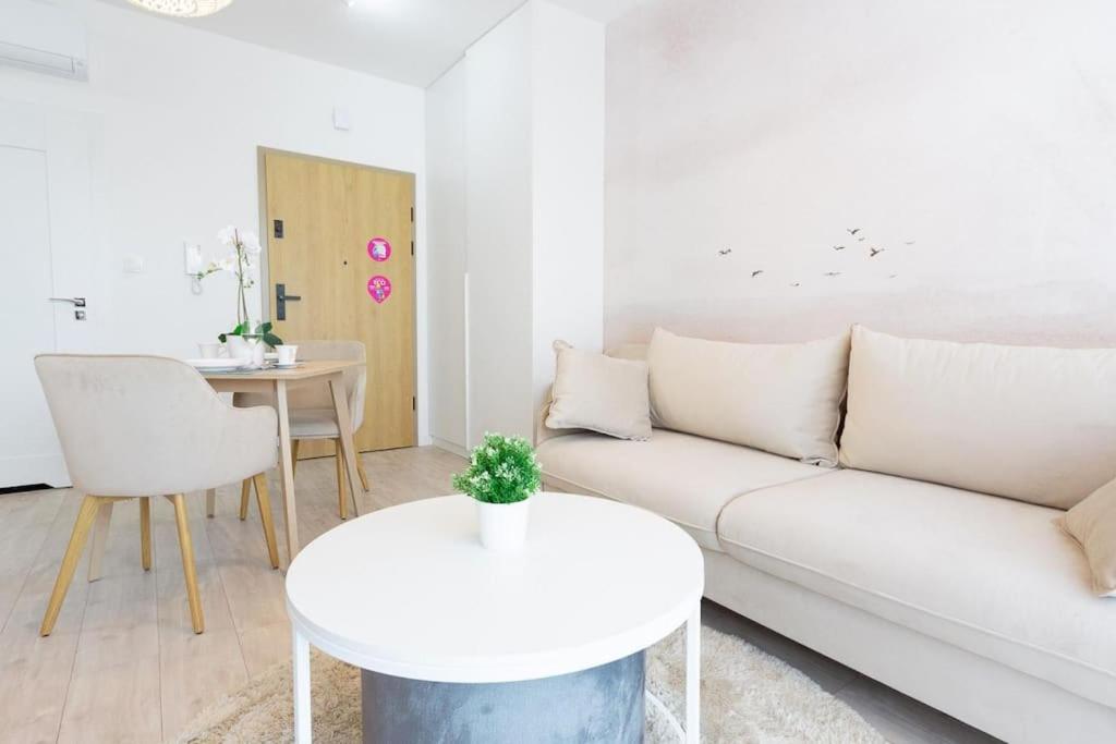 a white living room with a white couch and a table at VacationClub - Moon Residence Apartament 12 in Ustronie Morskie