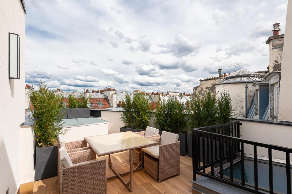 Un balcón con una mesa y sillas en un tejado. en Les Suites HCR, en París