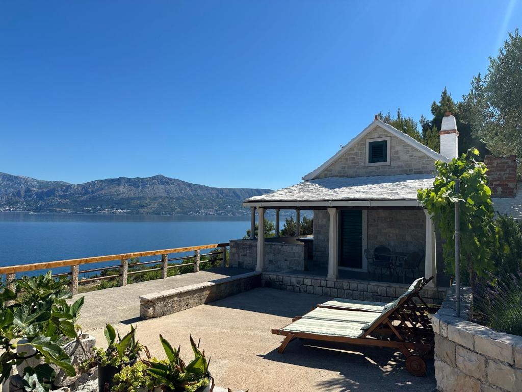 a house with a bench on a patio next to the water at Vacation House, PARKING INCLUDED, Lovrecina in Postira