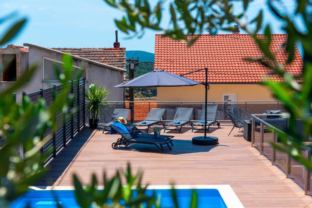 a deck with chairs and an umbrella on a building at Pool apartman Maja in Šibenik