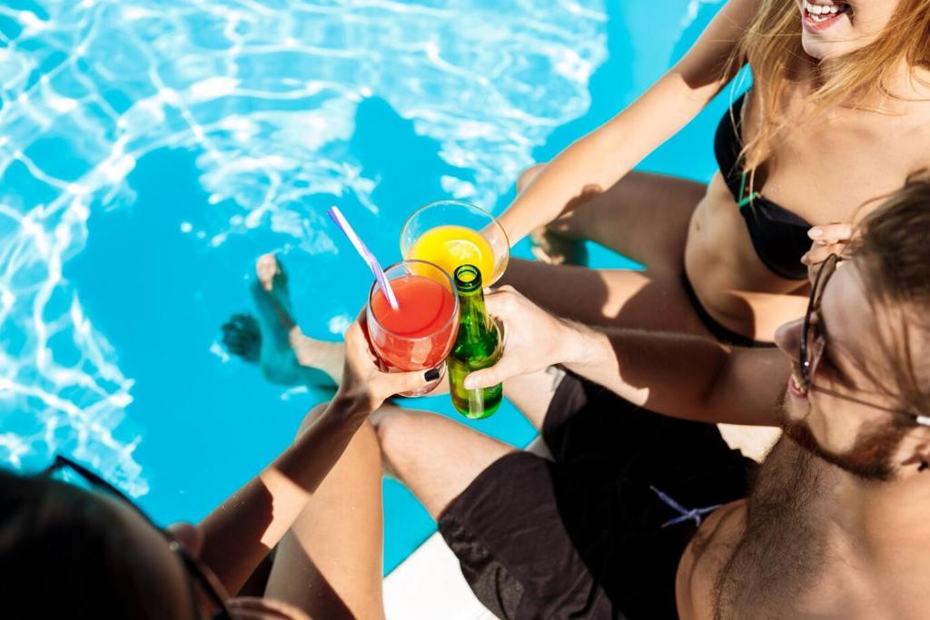 a group of people sitting around a pool drinking cocktails at Hotel MARINELLA parking wi-fi spiaggia attrezzata in Capo Vaticano