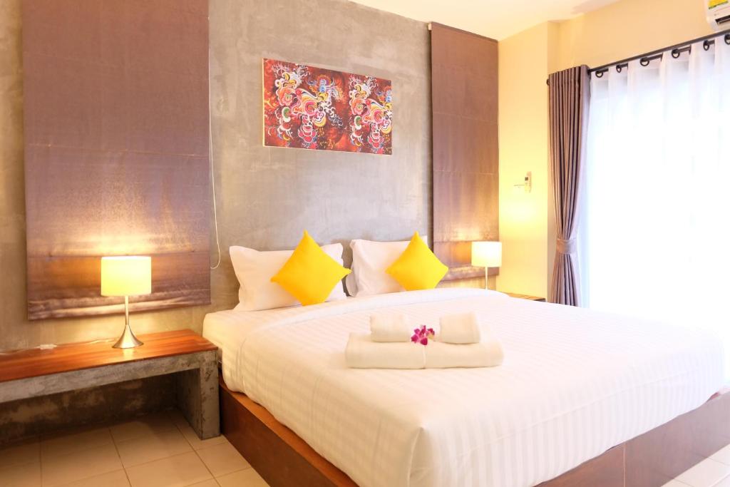 1 dormitorio con 1 cama blanca grande con almohadas amarillas en The Meeting House Aonang - self service, en Ao Nang Beach