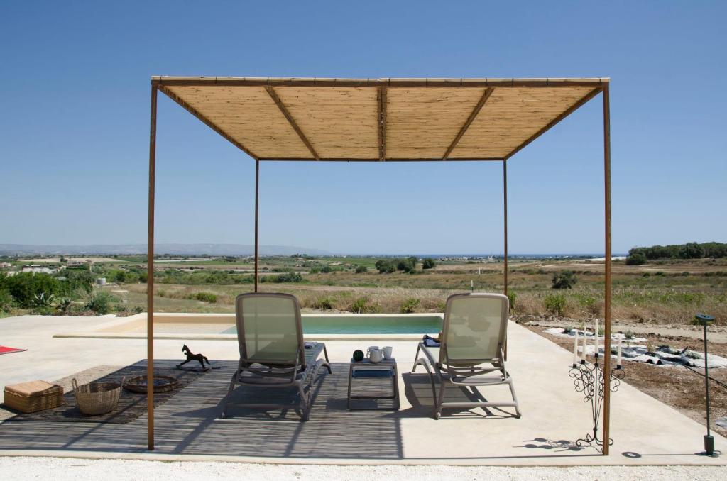 a gazebo with two chairs and a pool at NEW Exclusive Lodges, Marzamemi, Noto in Pachino