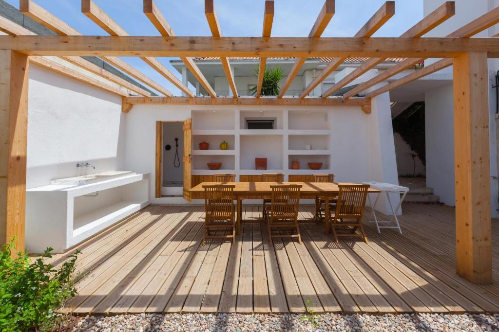 eine Holzterrasse mit einem Tisch und Stühlen in der Unterkunft FLH Jacaranda Costa Caparica Beach House in Costa da Caparica