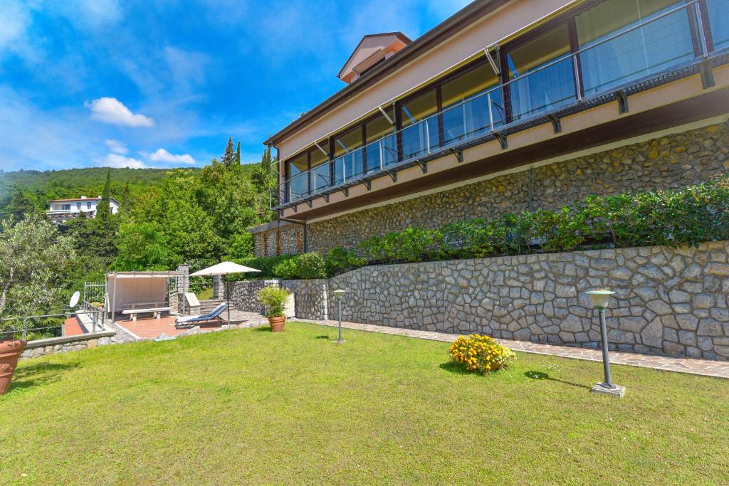 dom z kamienną ścianą i ogródkiem w obiekcie Apartments Villa Vosilla w mieście Opatija