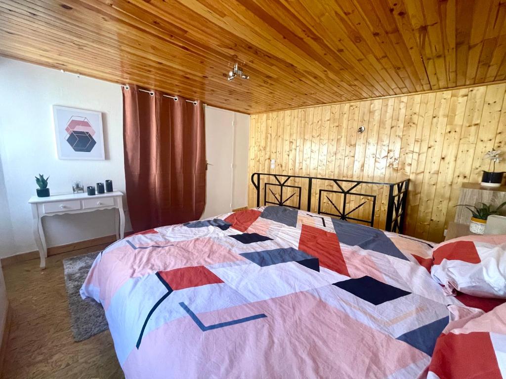 une chambre avec un grand lit avec un plafond en bois dans l'établissement Charmant gite esprit chalet, à Saint-Nazaire-le-Désert