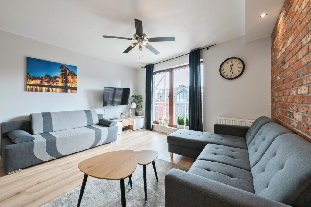 a living room with a couch and a table and a clock at Dom & House - Apartments Waterlane Island in Gdańsk