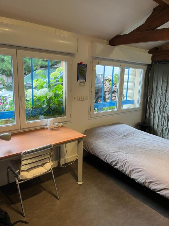 - une chambre avec un bureau, un lit et des fenêtres dans l'établissement Maisonnette de 34m2 proche de la Gare, à Houilles