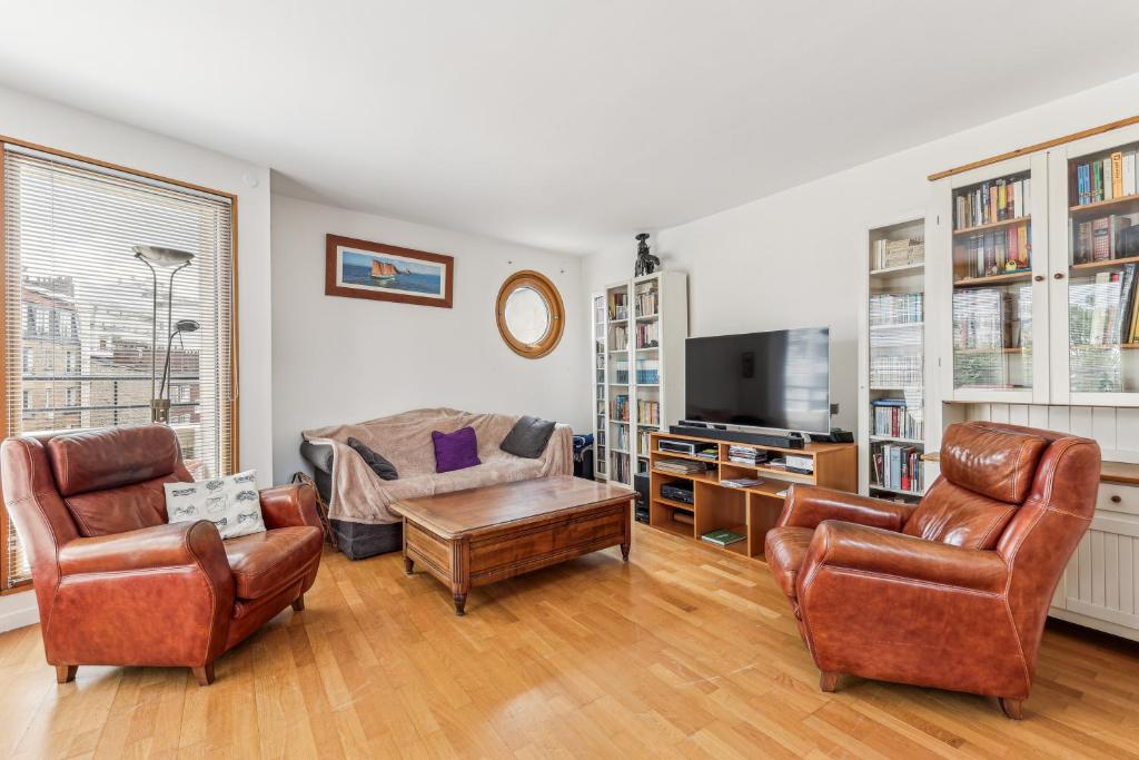 Il comprend un salon doté d'un mobilier en cuir et d'une télévision. dans l'établissement Appartement duplex dans le Saint Lambert by Weekome, à Paris