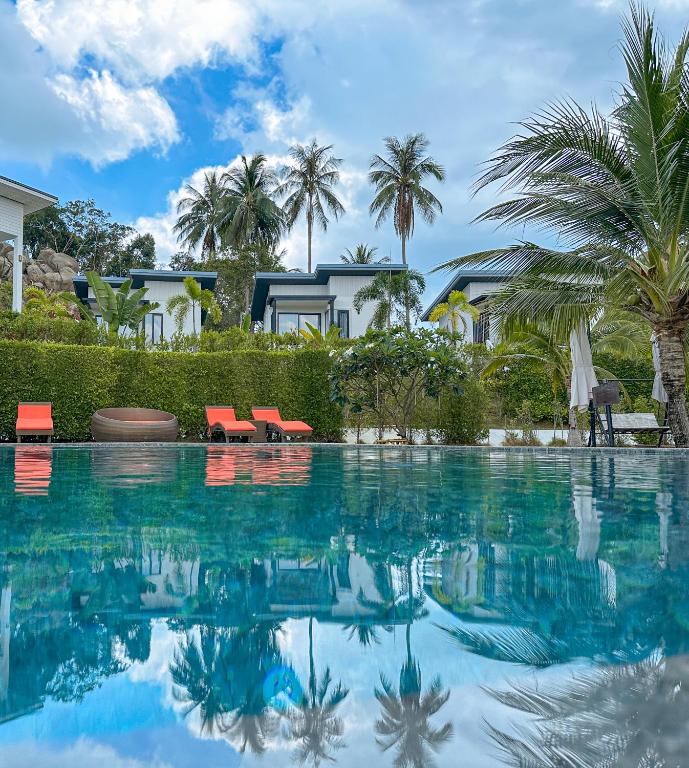 a pool with chairs and palm trees in front of a house at Naiwok Hills Resort in Haad Pleayleam
