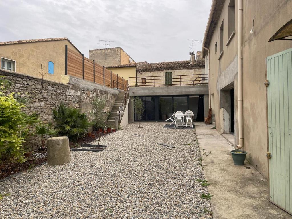 deux chaises blanches assises dans la cour d'un immeuble dans l'établissement Appartement Maison Saint Laurent dAigouze Village tournage Ici Tout Commence, à Saint-Laurent-dʼAigouze