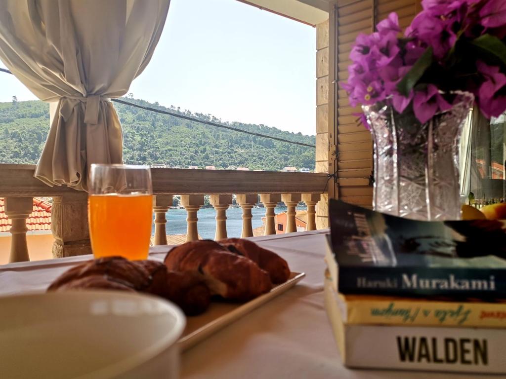 a table with a plate of food and a glass of orange juice at Apartman J&F in Smokvica