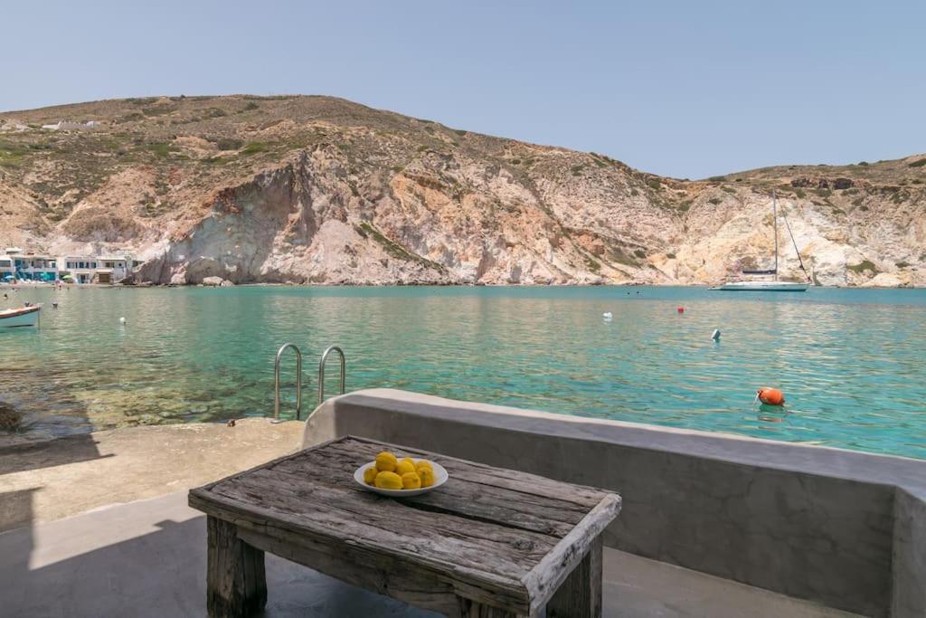 a bowl of fruit on a wooden table next to a body of water at Thavma Boathouse in Firopótamos
