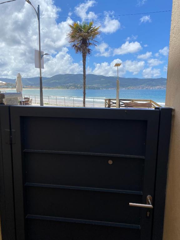 a black door with a view of the beach at Panxón Primera Linea Mar in Nigrán