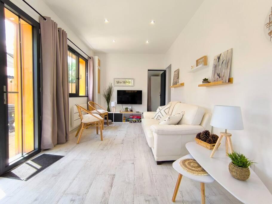 un salon avec un canapé blanc et une télévision dans l'établissement La Cabane C7, à Andernos-les-Bains